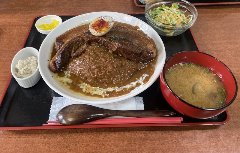 厚切りの豚の角煮をのせたカレーに、小鉢とお味噌汁を添えた定食